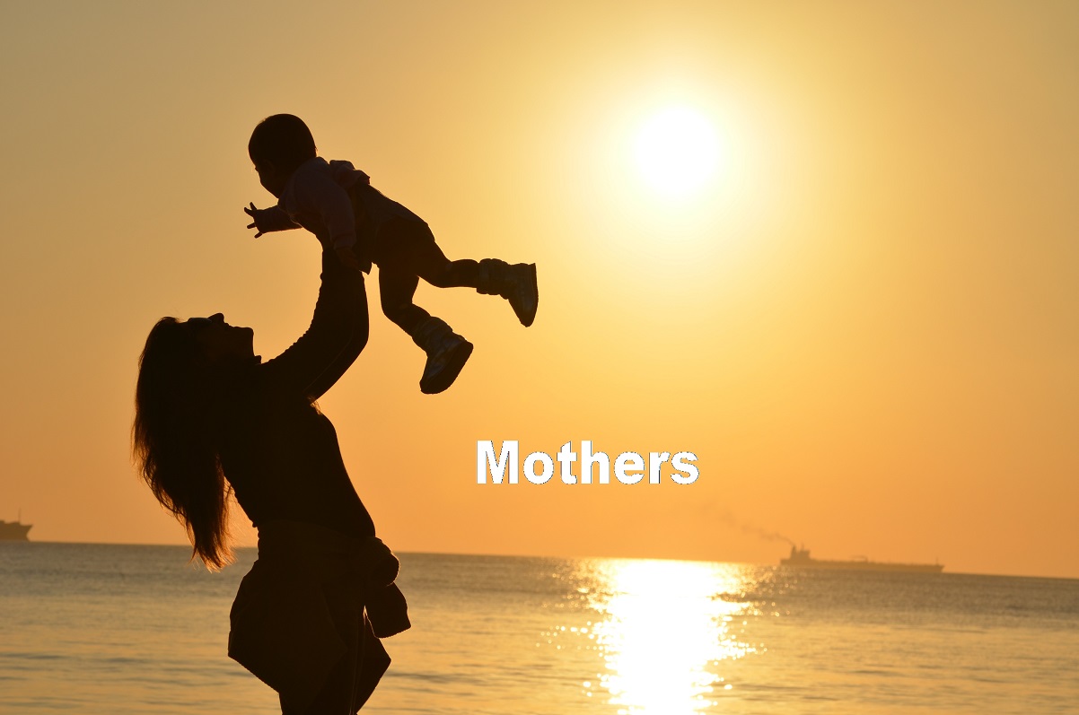 photo of mother holding a baby on the beach